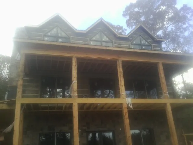 Dormers and porch framing on a large log home under construction — Roof Coating work by our crew in Spencerville