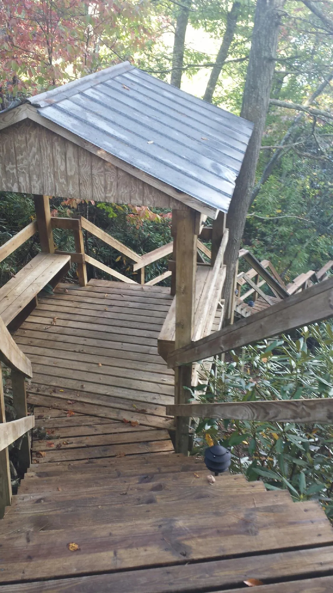 Metal roofed shelter over wooden steps on a wooded walkway — Skylight Repair & Installation work by our crew in Spencerville