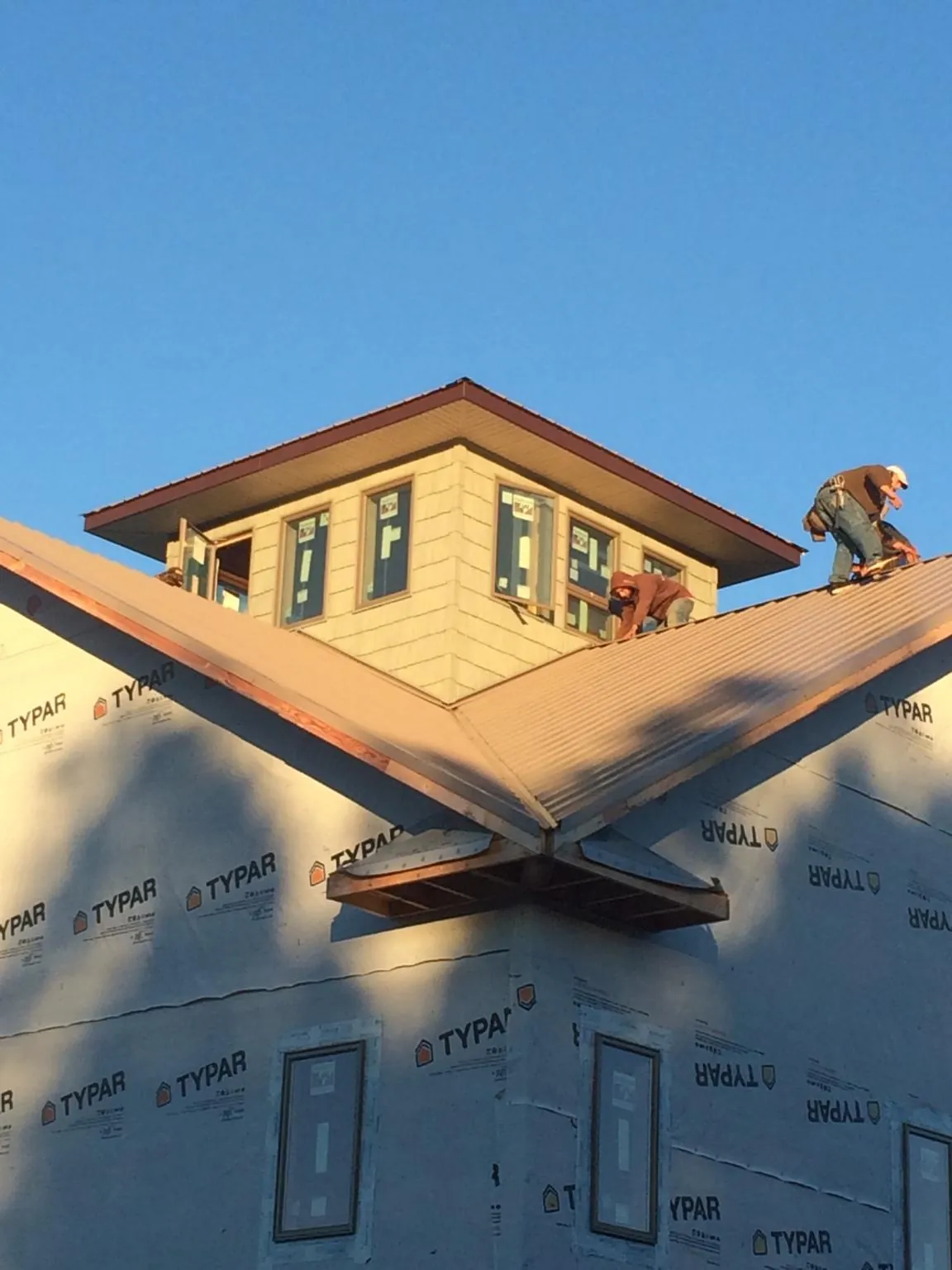 Roofers working around a rooftop cupola on a new metal roof at sunset — Roof Waterproofing in Spencerville by Roofing Brothers
